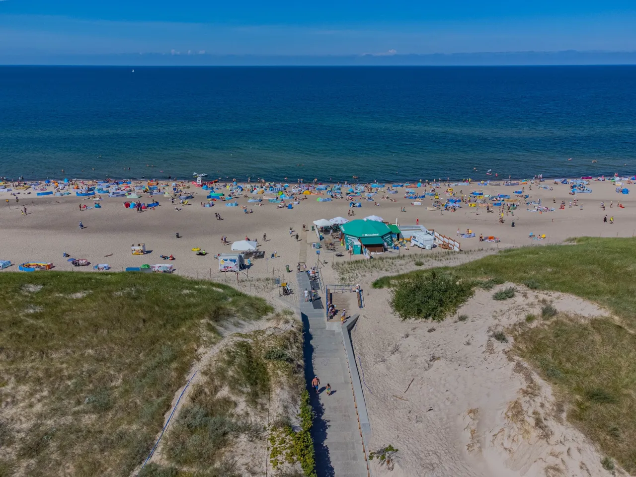 Tłum ludzi na plaży, idealne miejsce na wakacje. Zastanawiasz się, ile kosztuje nocleg nad morzem?