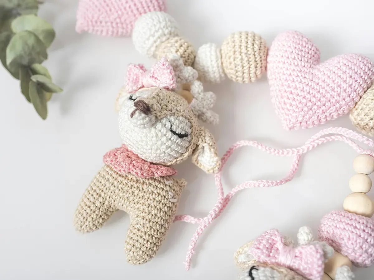 Urocze szydełkowanie pluszaki: jelonek z r&oacute;żową kokardką i serduszka, tworzące girlandę.