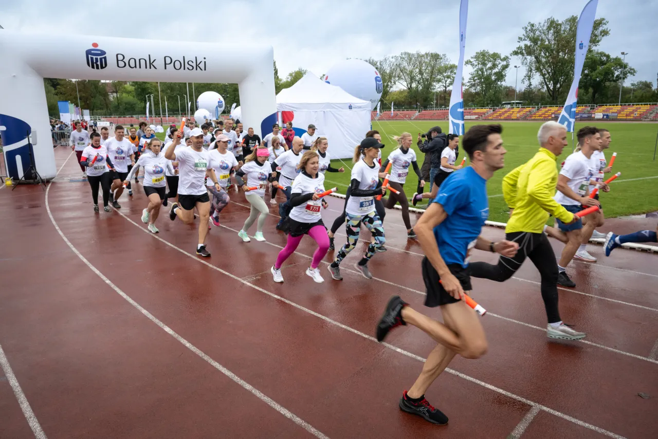 Biegaczka z uśmiechem biegnąca w parku o poranku, symbolizująca energię i radość z aktywności fizycznej