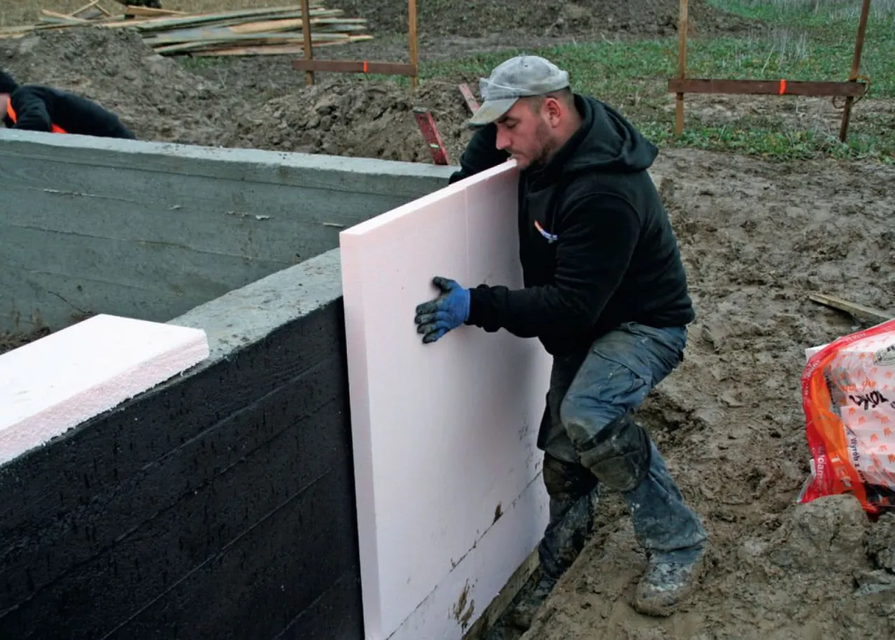 Budowlaniec dociepla fundamenty płytami XPS. Czy można zostawić odkryte fundamenty na zimę? Tak, jeśli są odpowiednio zabezpieczone.