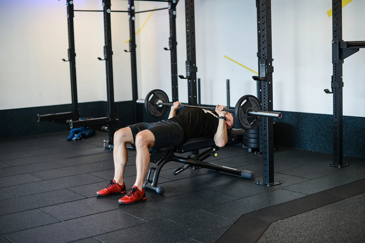 Mężczyzna wyciskający sztangę na ławce płaskiej
