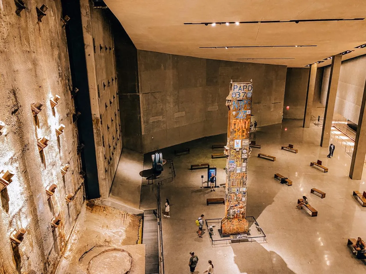 Wnętrze muzeum w Nowym Jorku upamiętniające 11 września. Monumentalna kolumna ozdobiona pamiątkami i napisami.