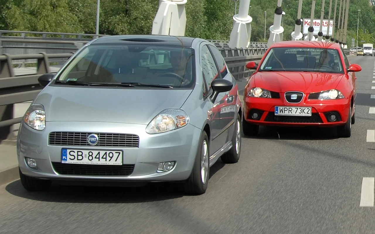 Srebrny Fiat i czerwony Seat jadą obok siebie. To ich pierwszy samoch&oacute;d, kt&oacute;ry zabiera ich na przygodę.