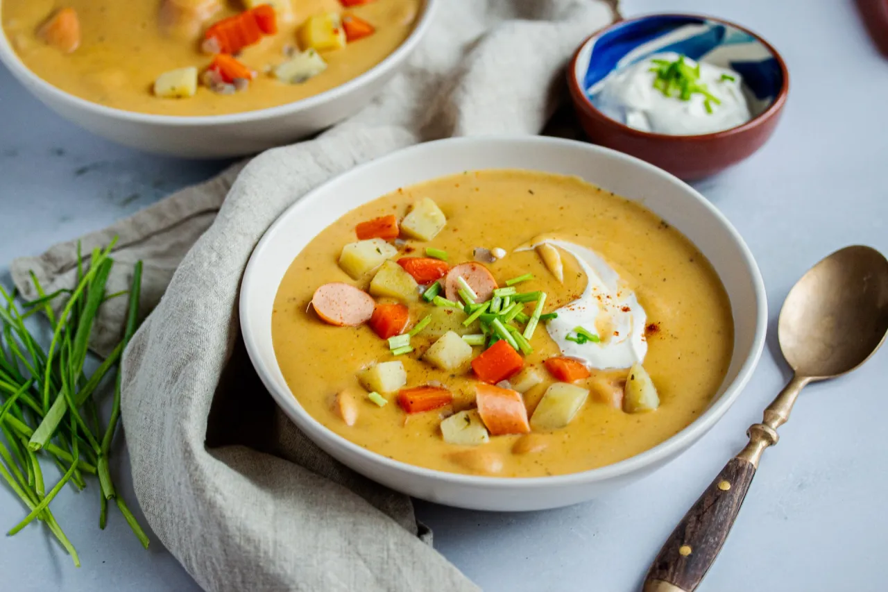 Verschiedene Schüsseln mit Kartoffel Karotten Suppe mit unterschiedlichen Toppings wie Croutons, Kräutern, Würstchen
