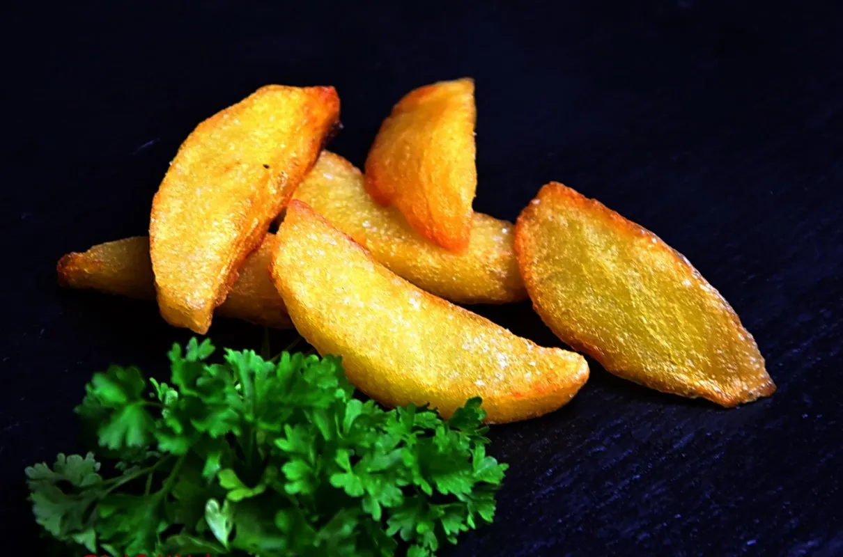 Złociste, chrupiące frytki belgijskie, idealne do przygotowania w domu. Świeża natka pietruszki dodaje koloru.