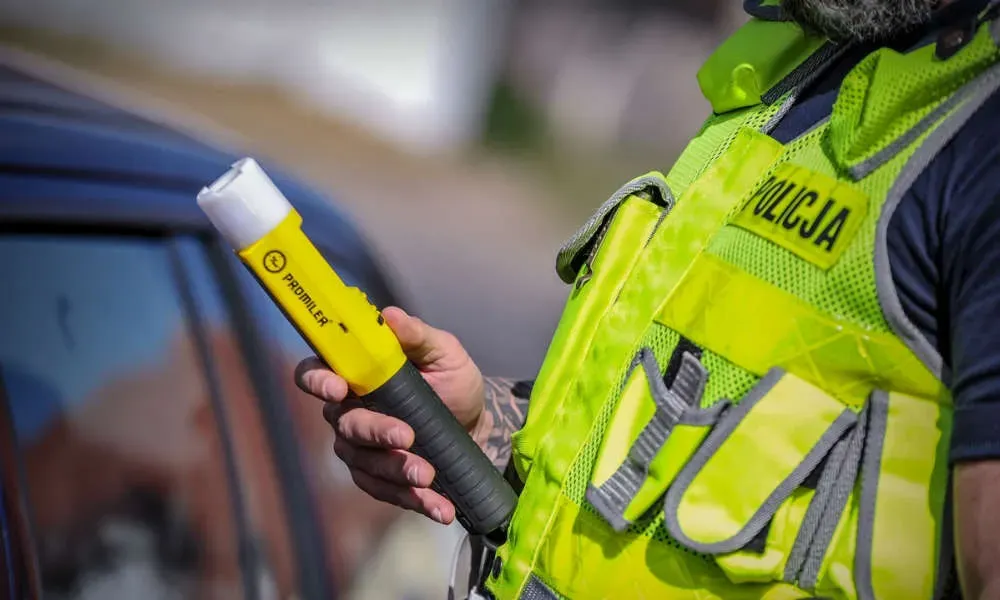 policjant przy drzwiach z alkomatem