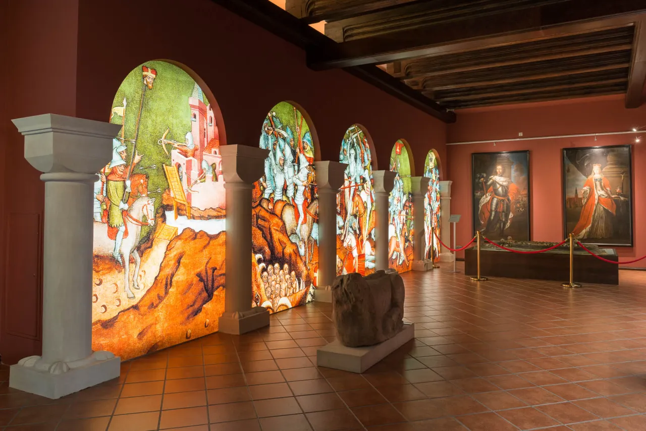 Wystawa w jednym z muzeów we Wrocławiu: podświetlane arkady z historycznymi scenami bitewnymi i portrety władców.