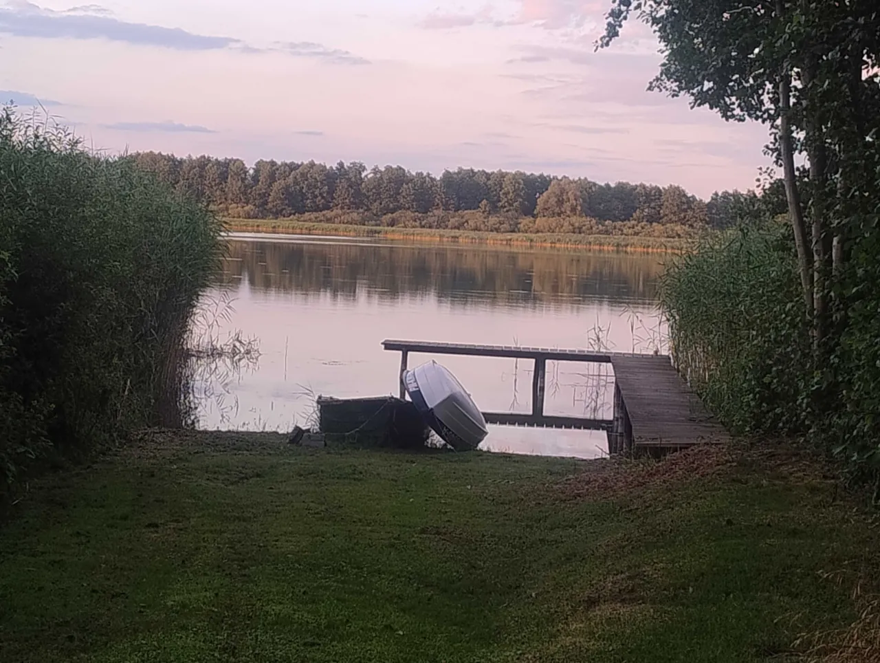Idealne miejsce, gdzie na ryby z noclegiem. Spokojna tafla jeziora, pomost i ł&oacute;dka czekają na wędkarzy.