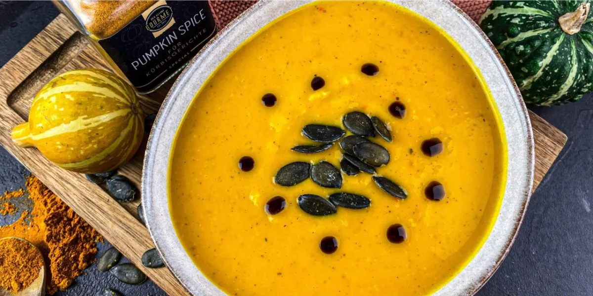 cremige Karotten K&uuml;rbis Suppe in einer Schale mit K&uuml;rbiskernen und Koriander garniert