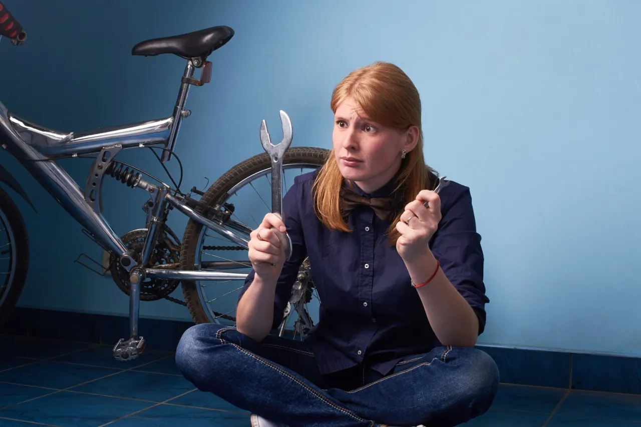 Zastanawiasz się nad zakupem roweru na firmę a VAT? Ta kobieta z kluczem w dłoniach i rowerem obok, wygląda na r&oacute;wnie zagubioną w przepisach.