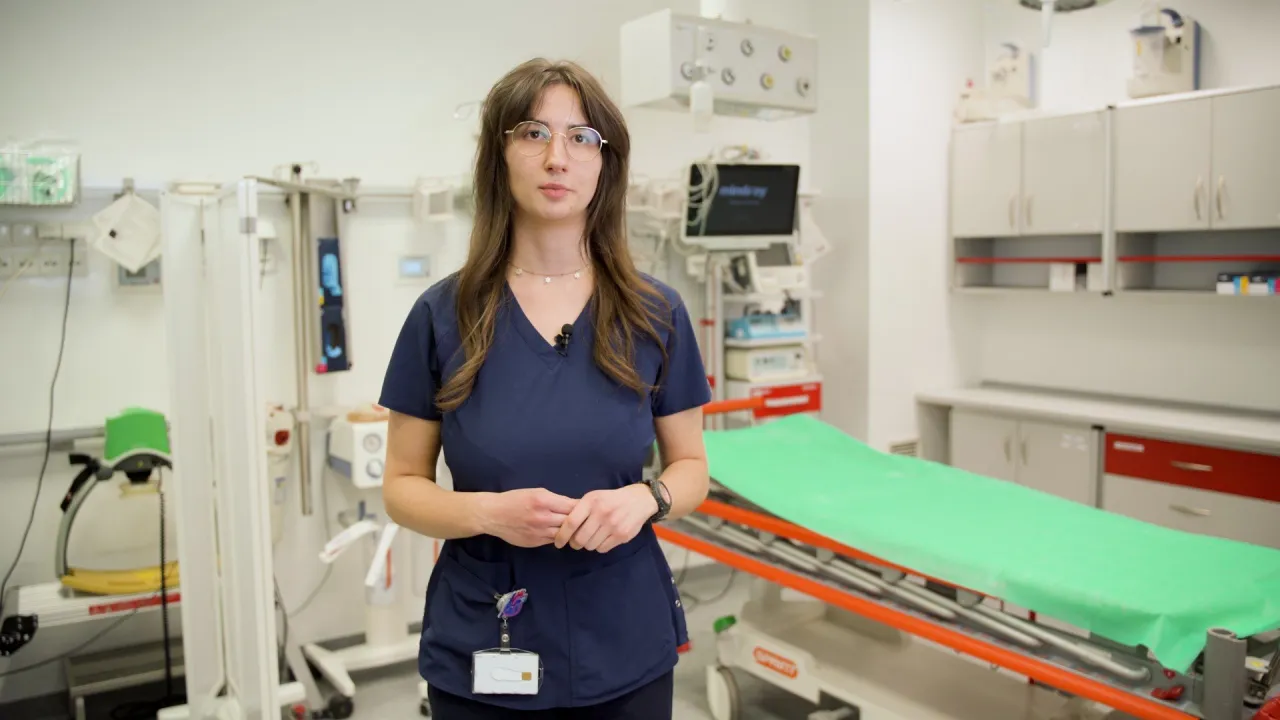 Młoda lekarka w gabinecie gotowa do przyjęcia pacjenta. W tle nosze i sprzęt medyczny, kiedy do lekarza.