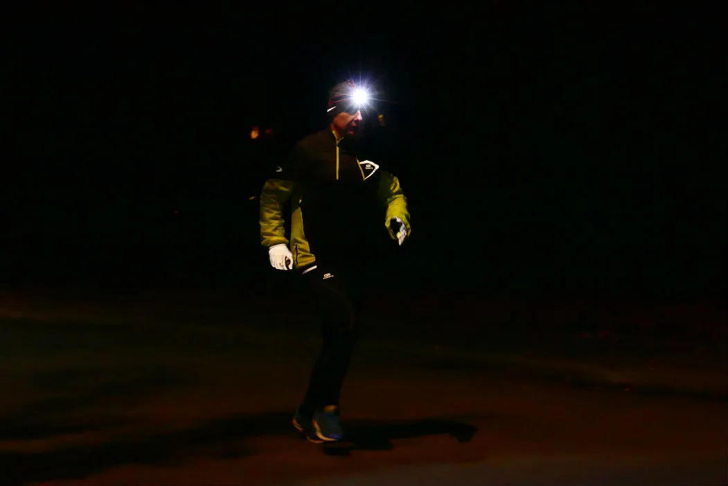 Biegacz z czołówką i odblaskami w nocy