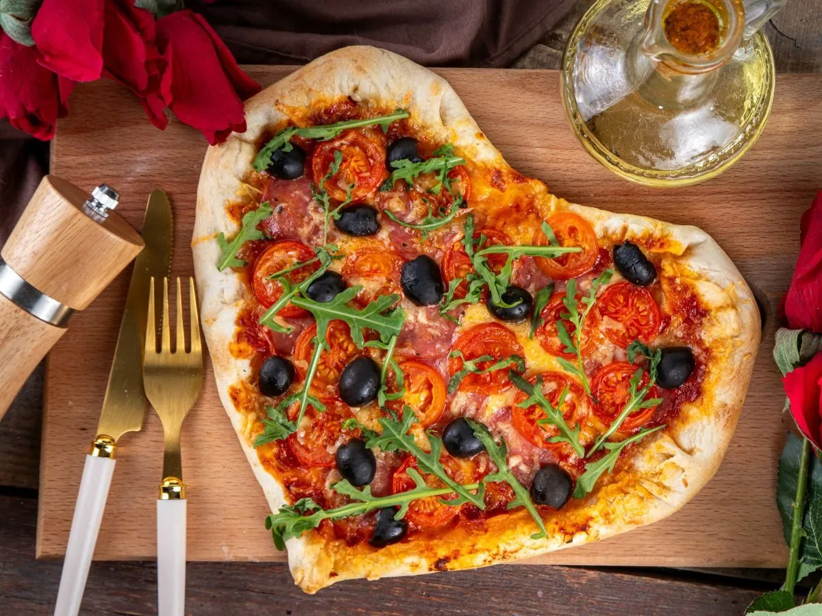 Pizza w kształcie serca z pomidorami, oliwkami i rukolą. Idealna inspiracja, co ugotować na kolację.