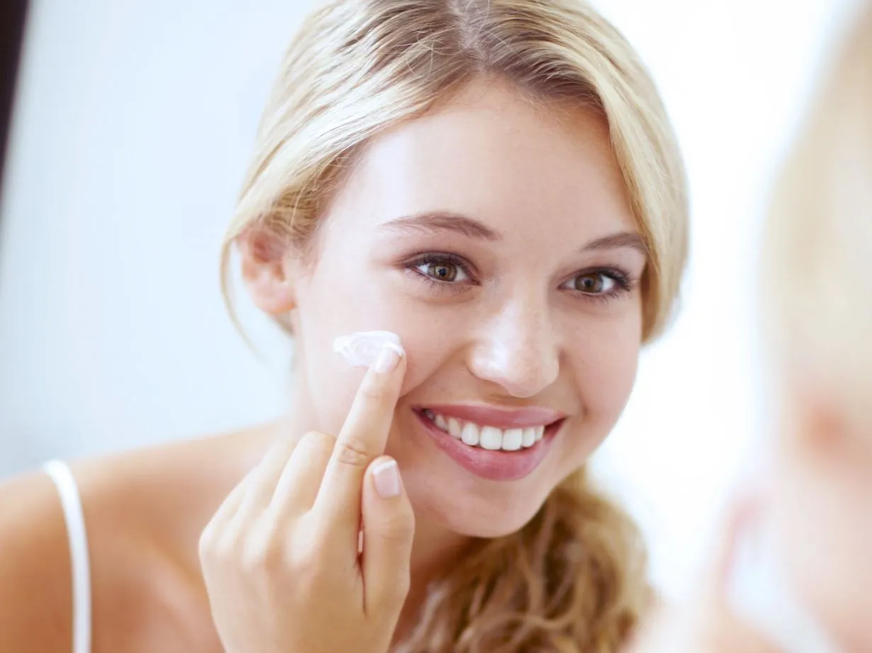 kobieta nakładająca krem nawilżający na twarz