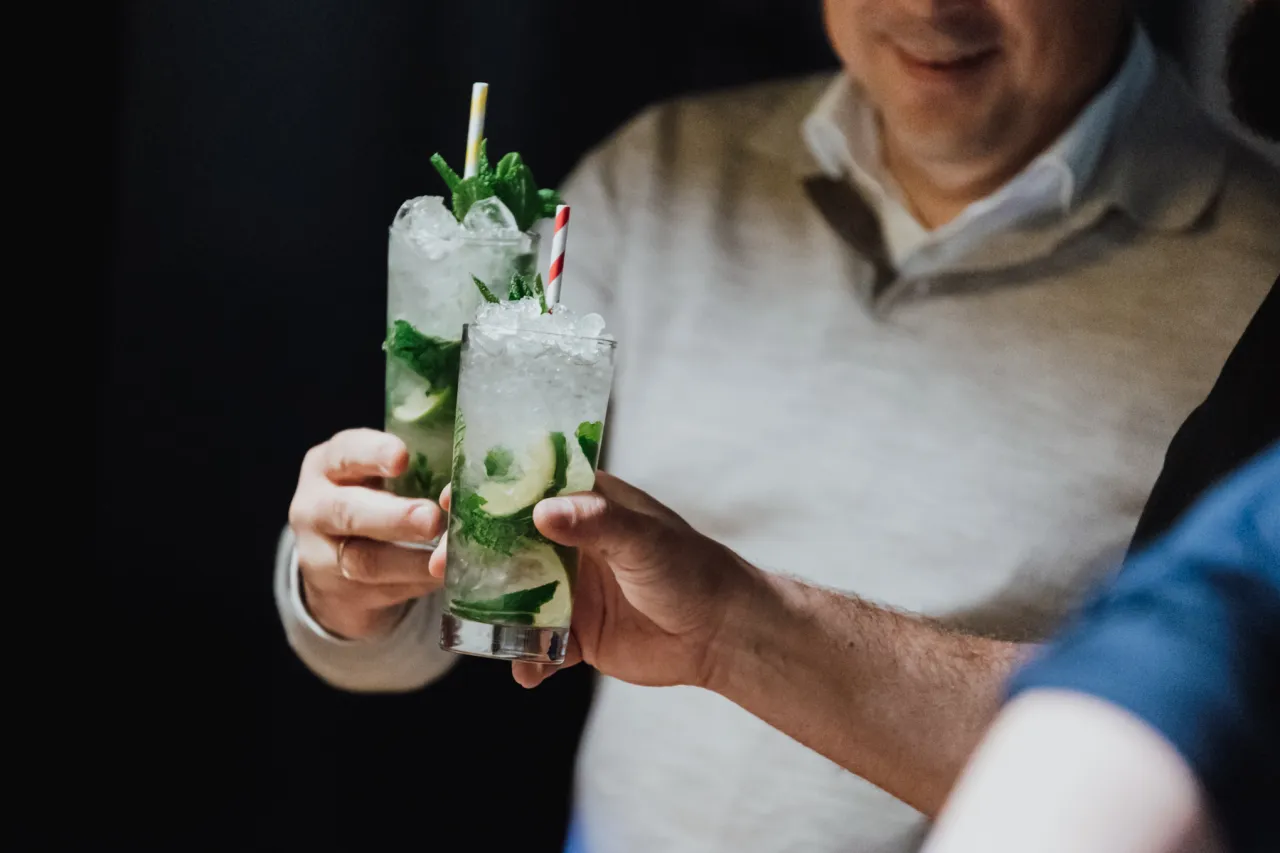 Jak zrobić idealne mojito domowym sposobem żeby nie było zbyt gorzkie? Dwa orzeźwiające drinki z miętą i limonką w szklankach z lodem.