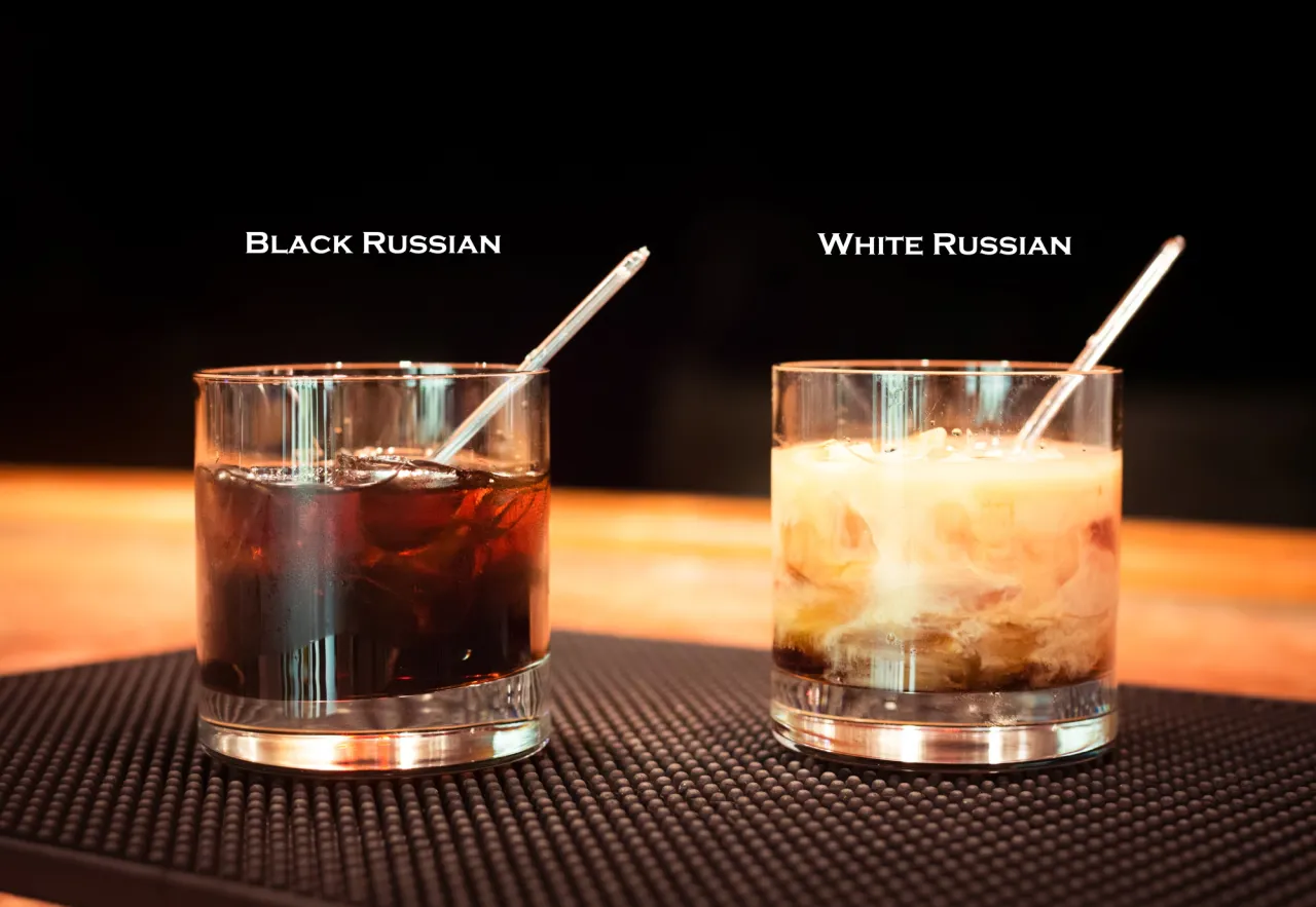 Dwa drinki na blacie: ciemny Black Russian i kremowy White Russian, każdy z kostkami lodu i słomką.