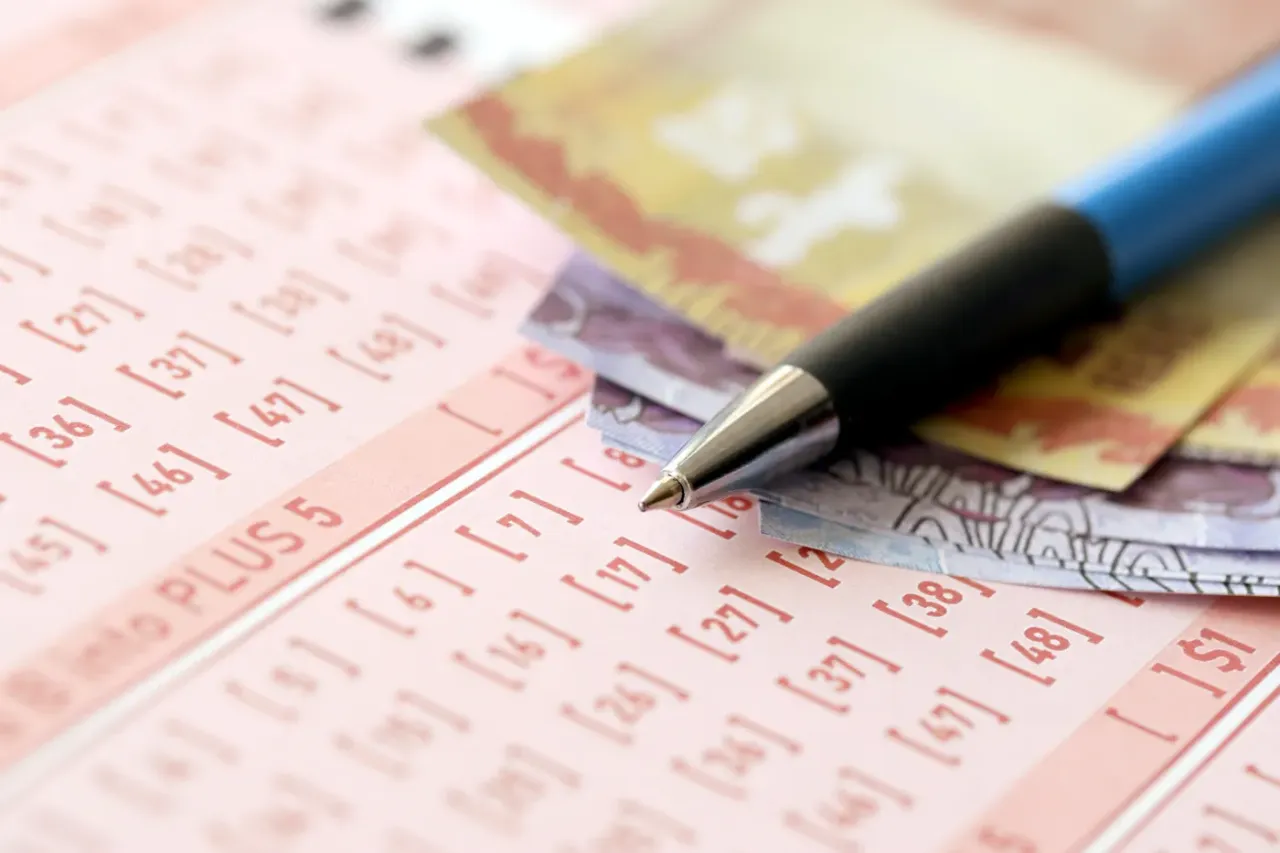 Długopis i pieniądze leżą na kuponie lotto, gotowe do gry w wielkiej loterii promocyjnej.