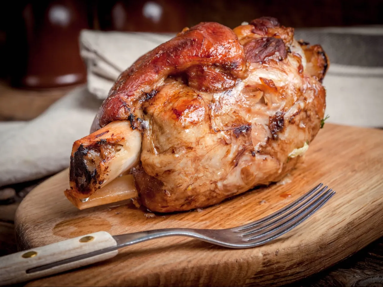 Soczysta, pieczona golonka na desce, gotowa do podania. Kluczowe jest, ile gotować golonkę przed pieczeniem, by była idealna.