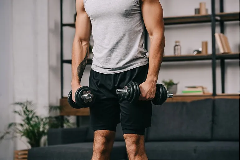 osoba ćwicząca w domu z hantlami