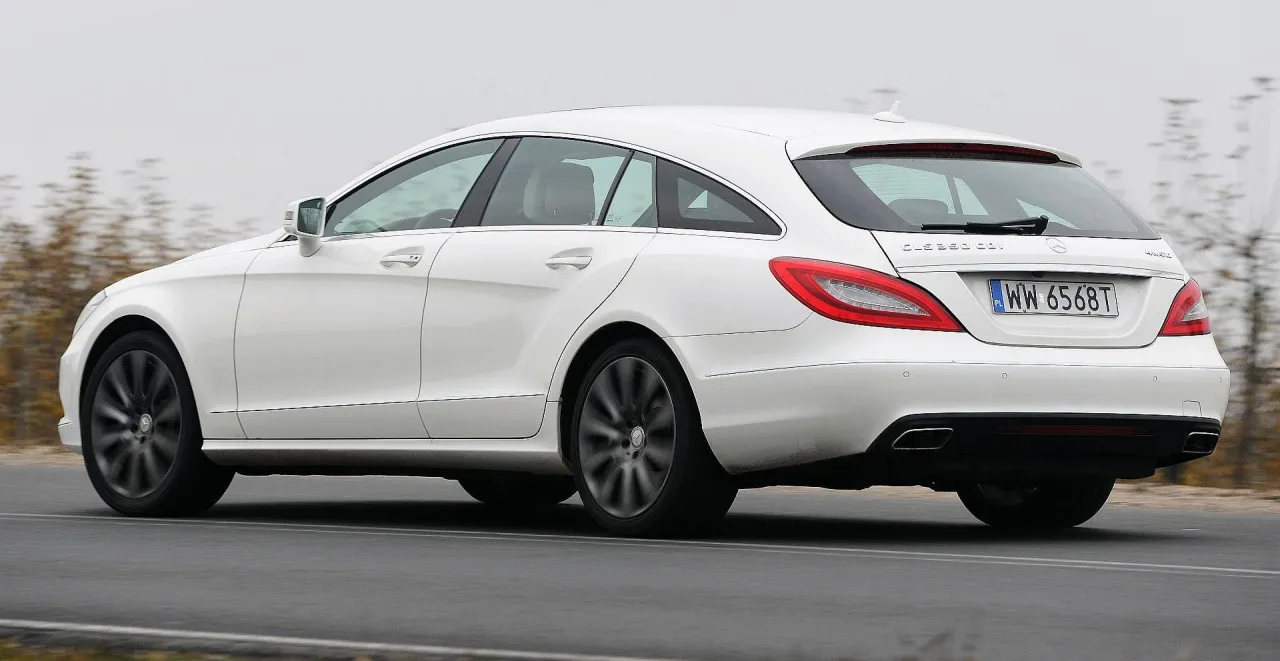 Biały Mercedes CLS 63 AMG Shooting Brake pędzi po drodze, ukazując swoje sportowe linie i eleganckie detale.