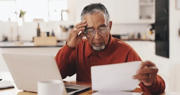 Osoba zmęczona, opierająca głowę na rękach przy biurku, symbolizująca wypalenie zawodowe