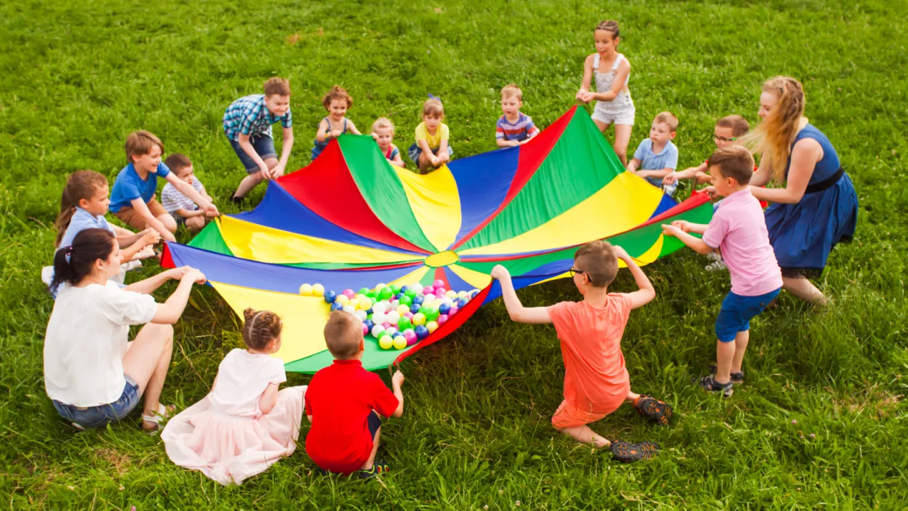dzieci bawiące się chustą animacyjną na boisku