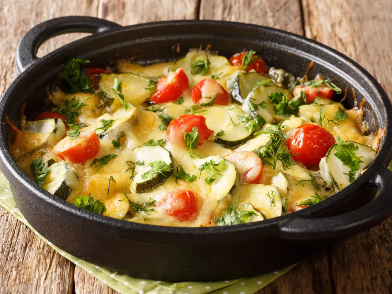 Zapiekanka z cukinią i pomidorkami, posypana serem i ziołami. Idealne co na obiad z cukinią, gdy chcesz zjeść coś pysznego i zdrowego.