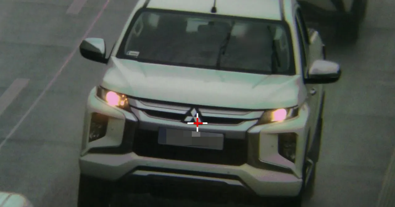 Biały pickup Mitsubishi z czerwonym celownikiem na tablicy rejestracyjnej. Prawdopodobnie czeka go mandat za zbyt wolną jazdę.
