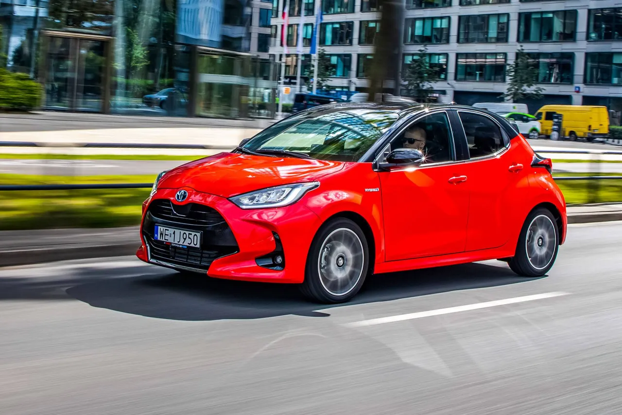 Czerwona Toyota Yaris Hybrid w ruchu miejskim. Zastanawiasz się, ile pali Toyota Yaris Hybrid? Ten model jest znany z niskiego spalania.