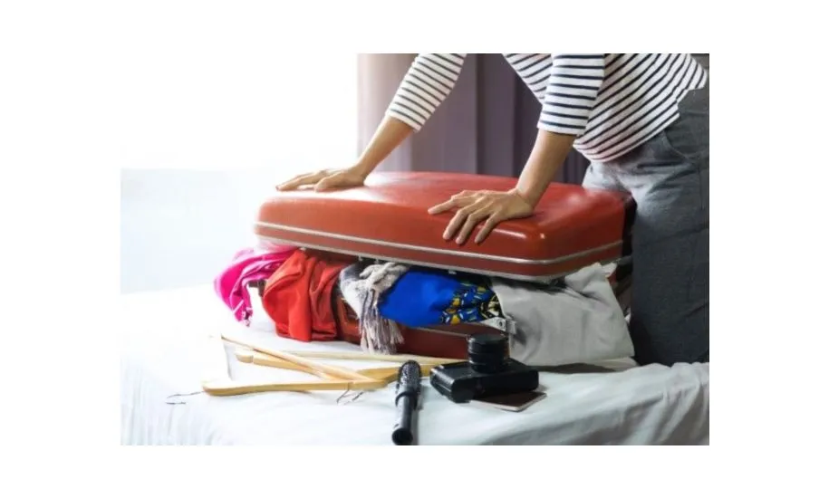 osoba pakująca kurtkę do walizki