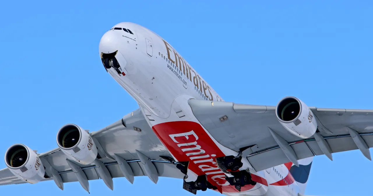 Ogromny samolot Emirates wznosi się na tle błękitnego nieba. Zastanawiasz się, ile trwa lot z Polski do Jordanii?