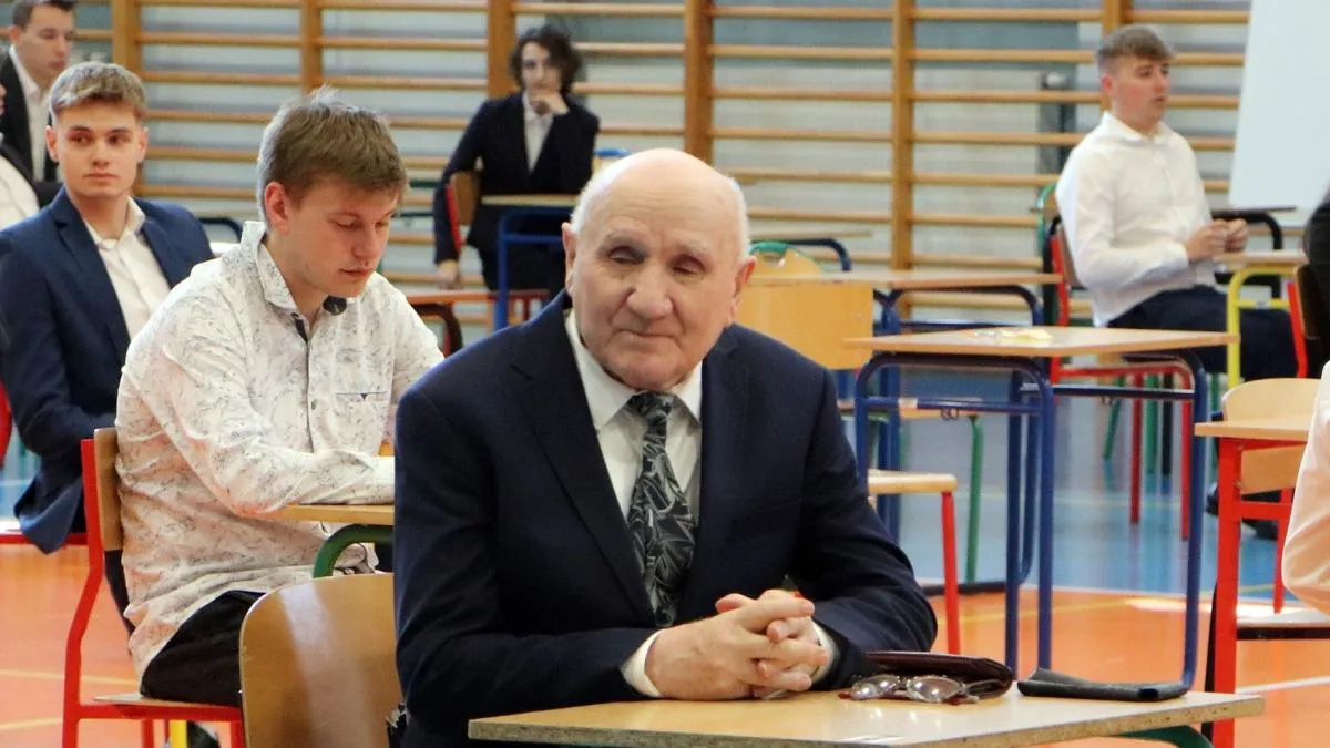 Uśmiechnięty maturzysta trzymający świadectwo dojrzałości