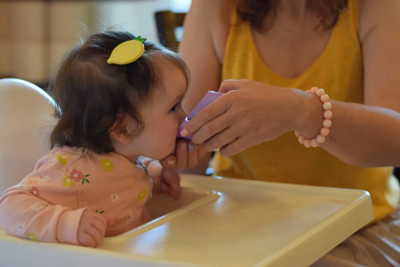 mama w zabudowanej piżamie, dziecko pije wodę z kubka