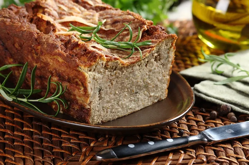 Domowy pasztet mięsny na desce do krojenia z ziołami
