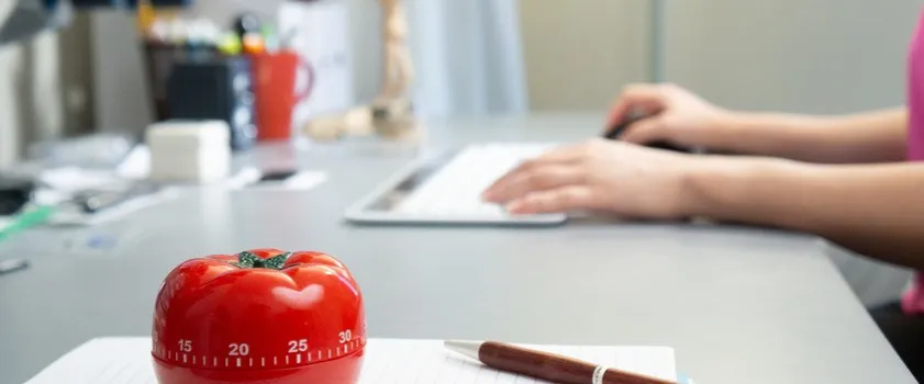 Osoba korzystająca z techniki Pomodoro z zegarem i notatkami