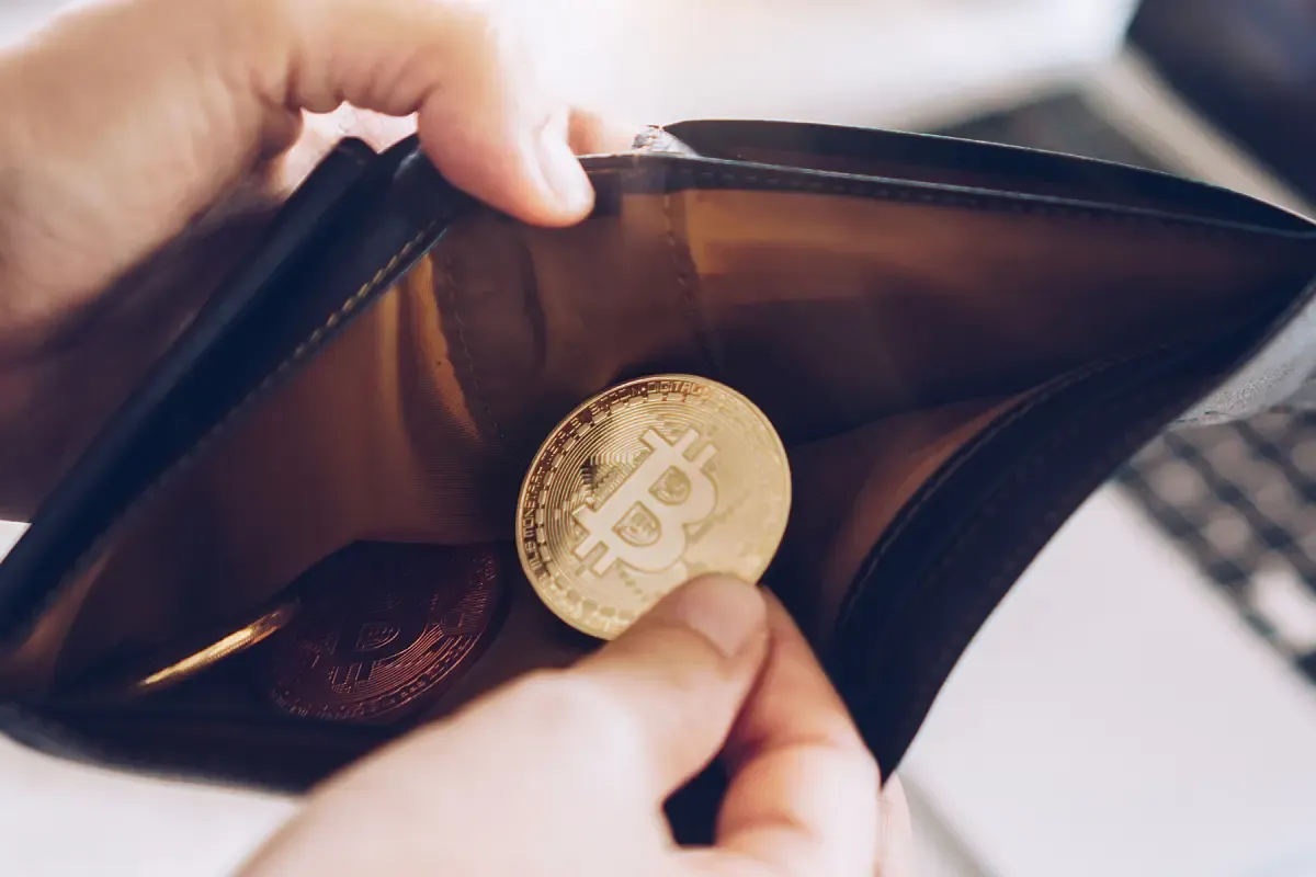 Złote monety z symbolem Bitcoina w portfelu. Rozpoczynasz swoją przygodę, jak inwestować w kryptowaluty.