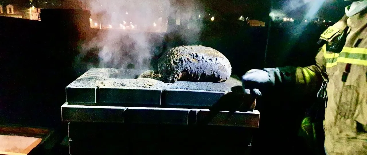 Strażak w akcji, pr&oacute;buje dowiedzieć się, czym gasić sadze w kominie. Dym unosi się z paleniska.