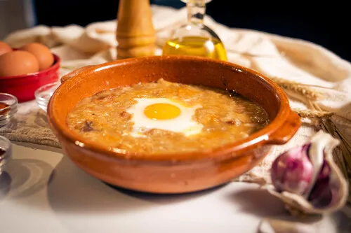 Sopa de ajo con ingredientes separados (ajos, pan duro, piment&oacute;n, aceite, caldo, huevo, jam&oacute;n)