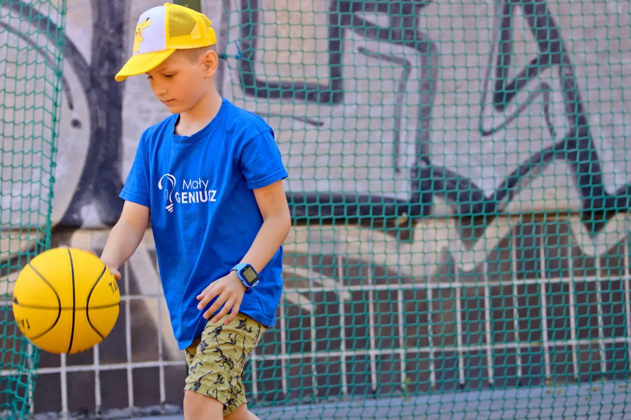 Dziecko grające w koszyk&oacute;wkę z uśmiechem