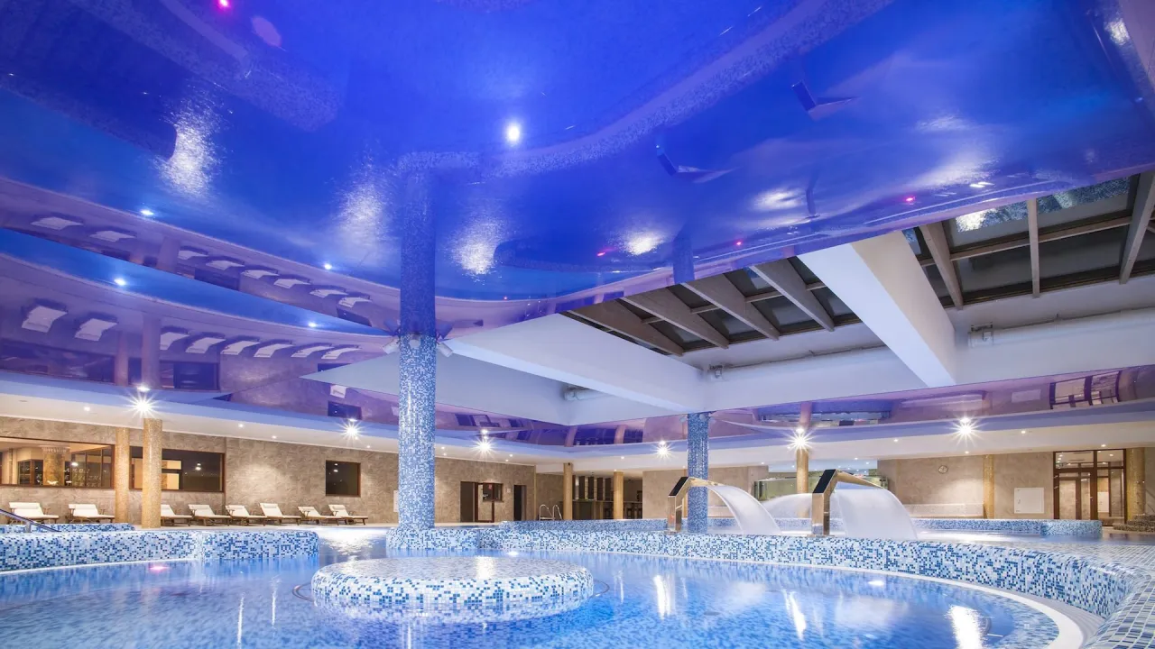 Wieniec-Zdrój sanatorium: basen z wodospadami i leżakami. Sprawdź ceny pobytu i relaksuj się w luksusowym wnętrzu.