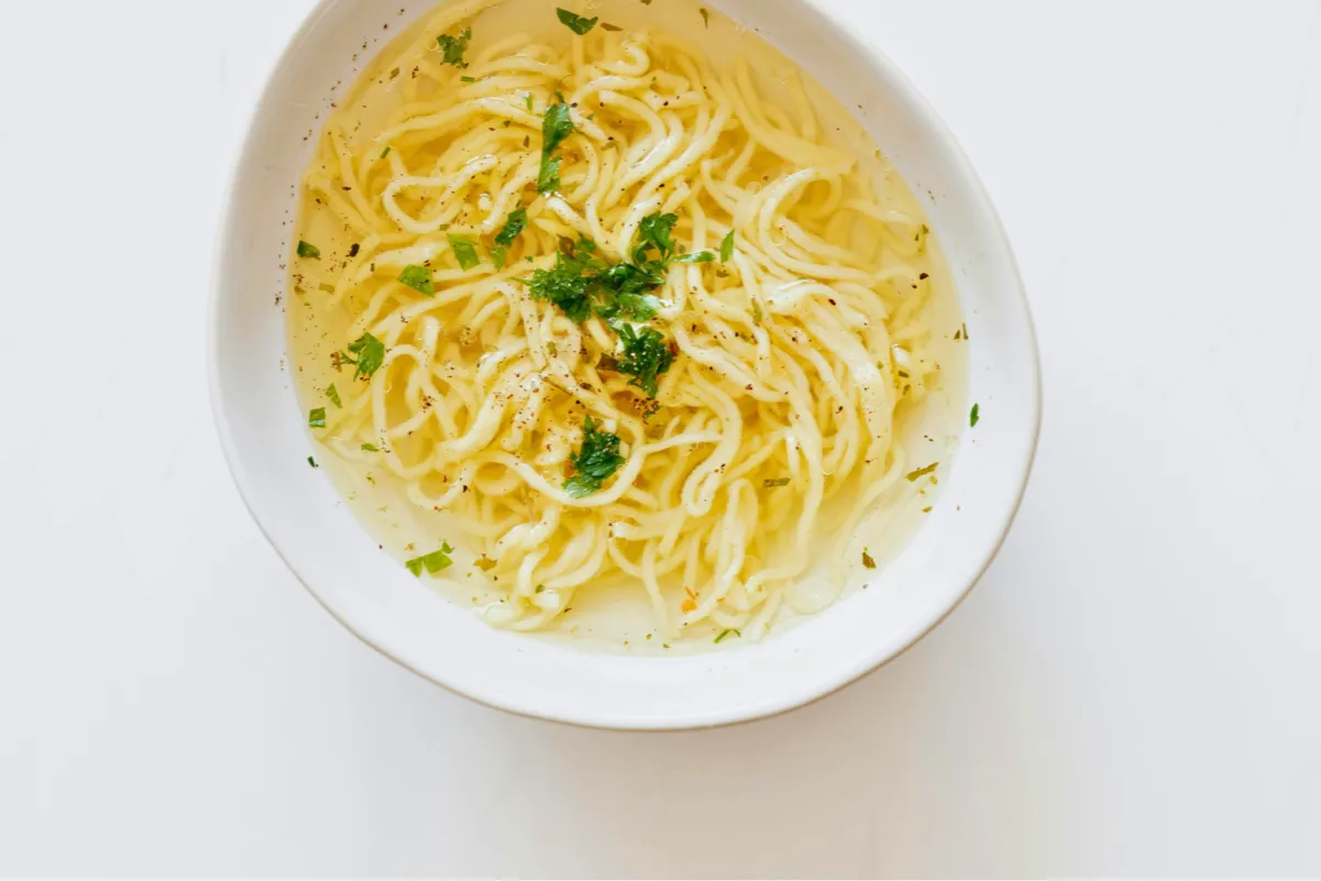 Miseczka z bulionem i makaronem, posypana natką. Czy maggi jest zdrowe? To pytanie zadaje sobie wiele osób, szukając odpowiedzi w prostych daniach.