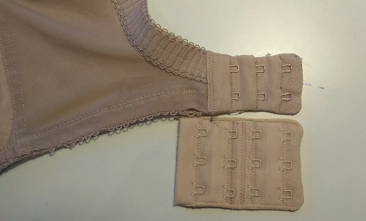 Jak przerobić biustonosz? Pokazano fragment cielistego biustonosza z zapięciem i dodatkowy panel z haczykami.