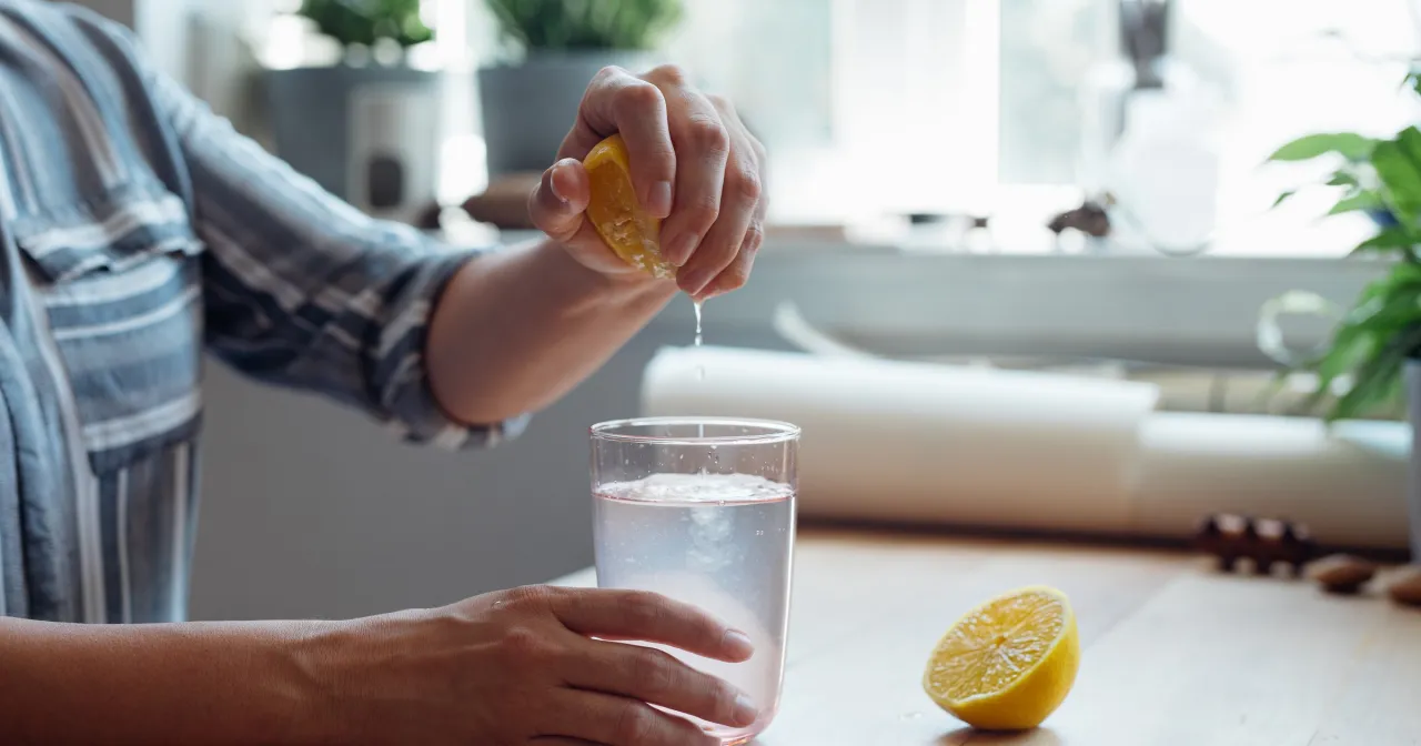 Osoba pijąca wodę z cytryną