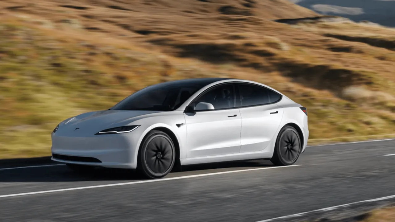 Biała Tesla Model S pędzi po drodze wśród wzgórz. Zastanawiasz się, ile kosztuje Tesla Model S?