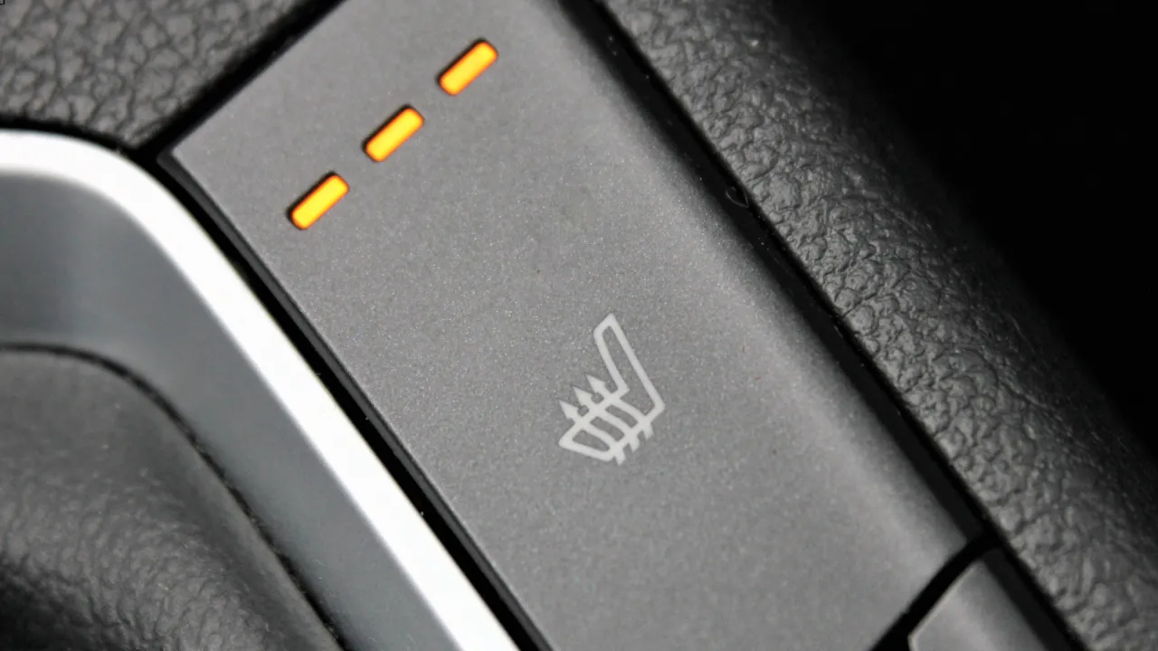 Przycisk podgrzewania foteli z trzema pomarańczowymi diodami. Gdy nie działa, warto sprawdzić, jak naprawić podgrzewanie foteli.