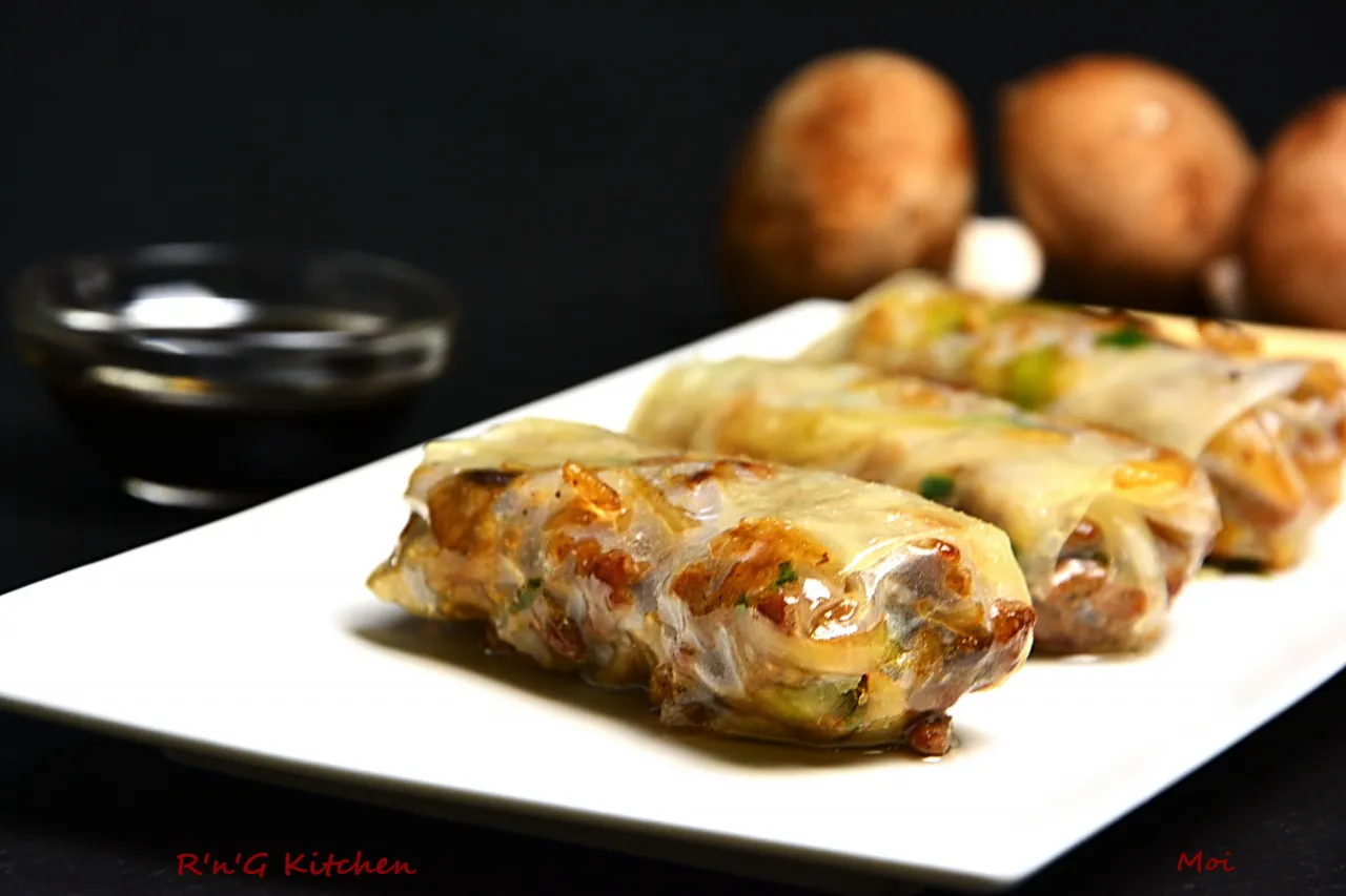 Chrupiące sajgonki z mięsem mielonym, podane na białym talerzu z miseczką sosu.