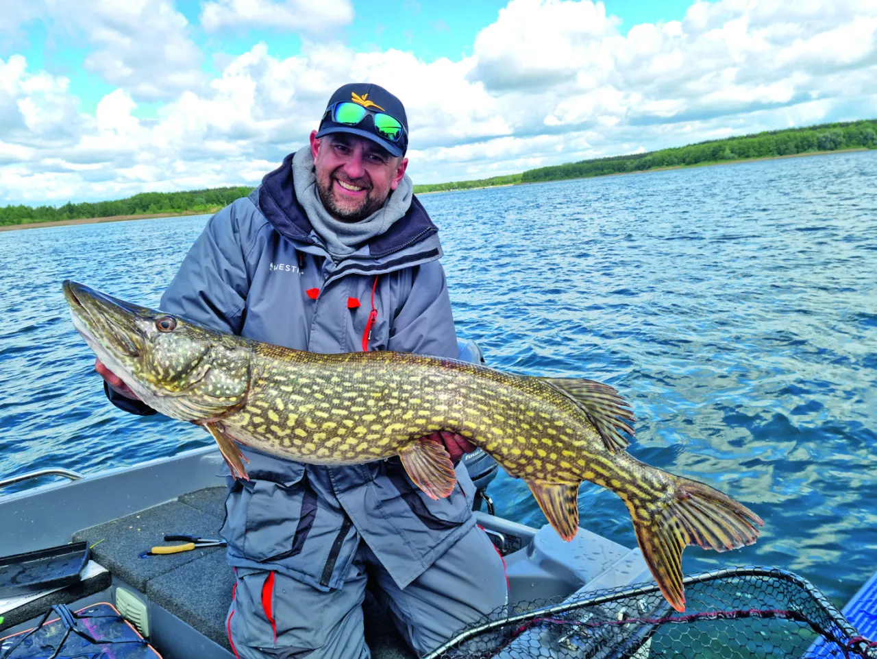 Szczęśliwy wędkarz trzyma ogromnego szczupaka złowionego na żywca. Wędka musiała być mocna!