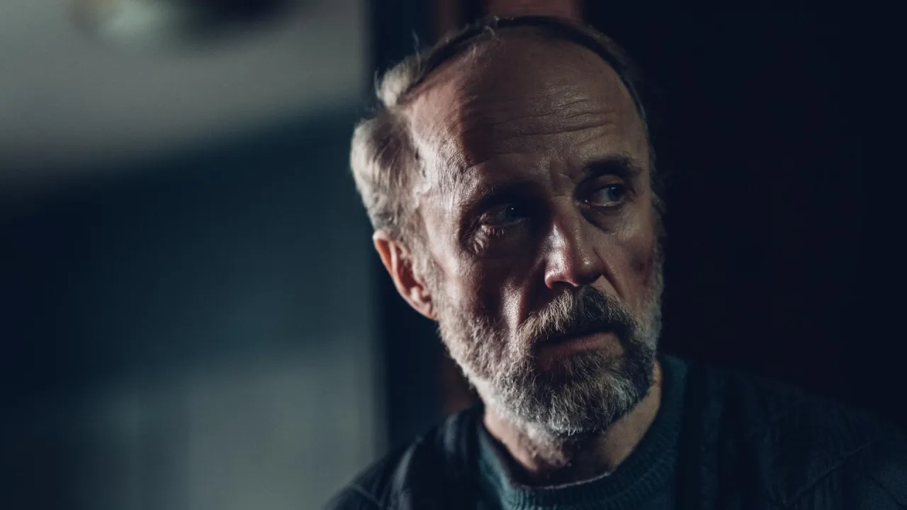 Portret mężczyzny z siwą brodą i zmarszczkami. Zastanawia się, w jakich filmach grał Łukasz Simlat.