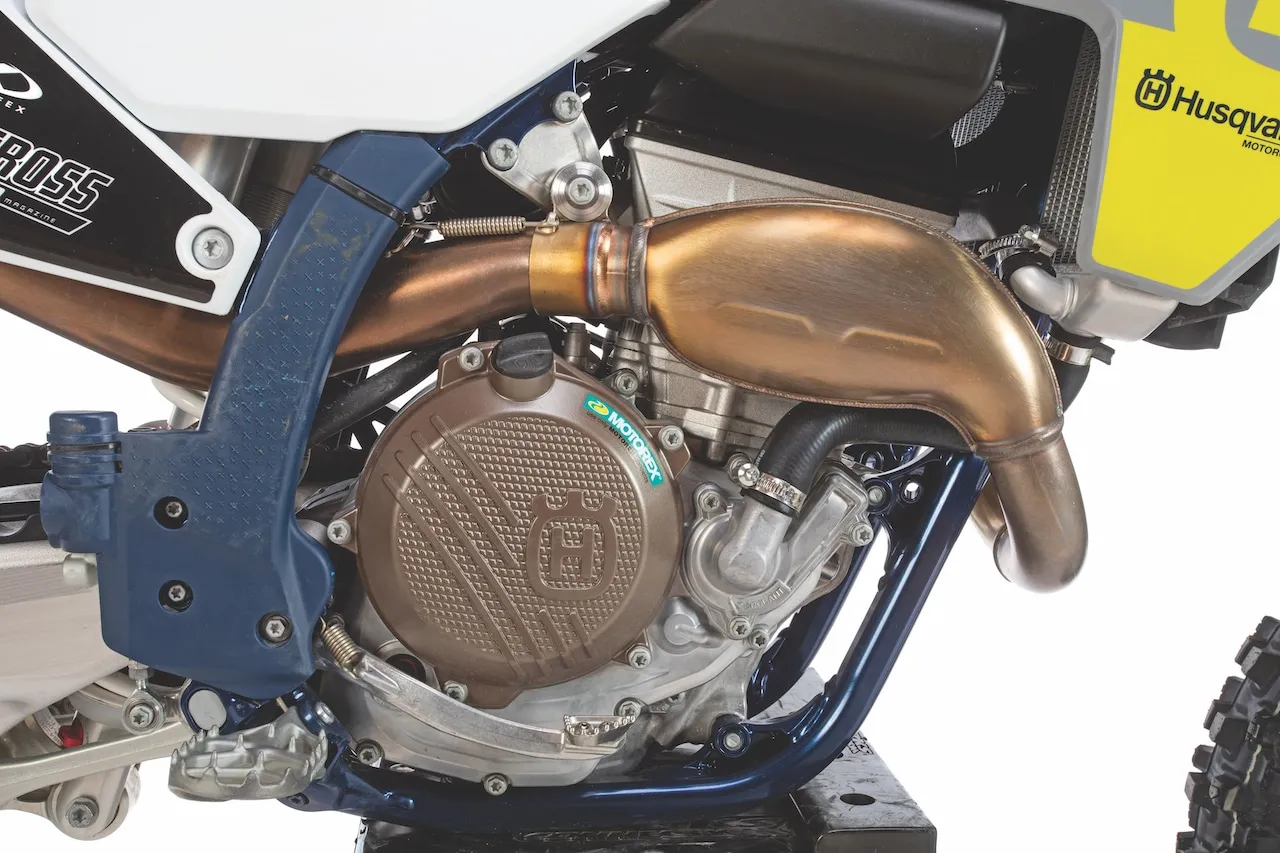 Silnik motocykla Husqvarna FC 250 z miedzianym wydechem i brązową pokrywą.