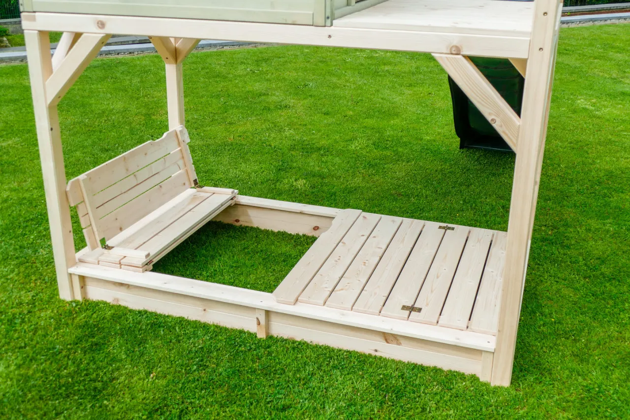 dziecko bawi się w drewnianej piaskownicy